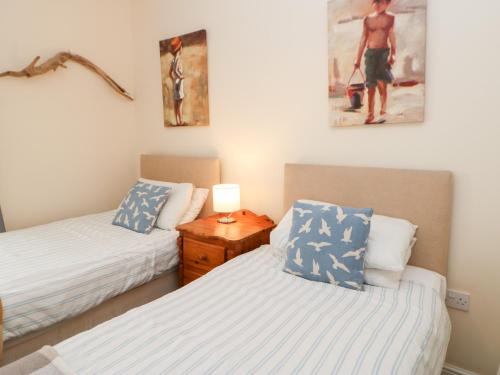 a bedroom with two beds and a lamp on a table at Driftwood Apartment in Amble
