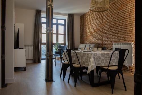 a dining room with a table and chairs and a brick wall at Costanilla Turismo in Zamora