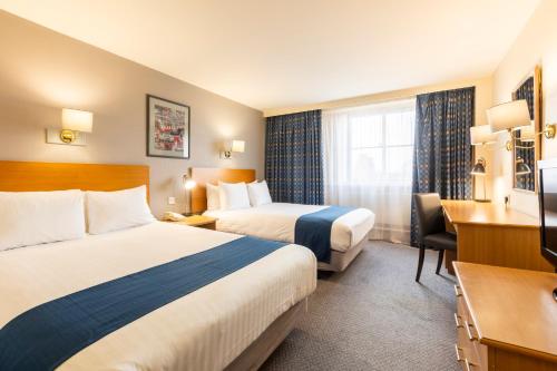 a hotel room with two beds and a desk at Holiday Inn London Sutton, an IHG Hotel in Sutton