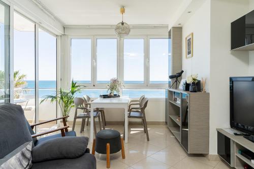 ein Wohnzimmer mit einem Tisch, Stühlen und Meerblick in der Unterkunft MONKÓ ON THE ROCK in Torremolinos