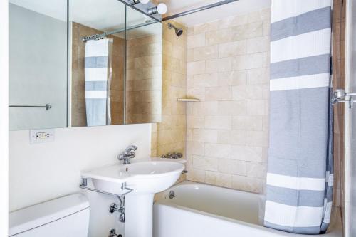ein Badezimmer mit einem Waschbecken, einem WC und einer Badewanne in der Unterkunft Midtown E 1BR w WD Doorman nr Central Park NYC-532 in New York