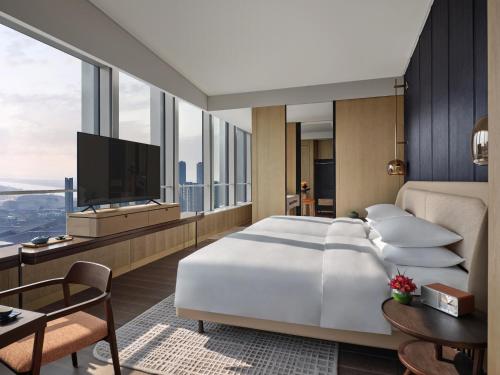 a bedroom with a large white bed and a tv at Andaz Nanjing Hexi in Nanjing