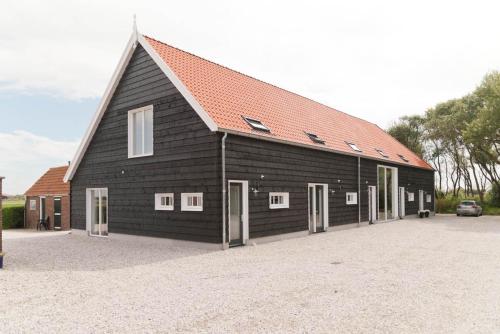 a large black barn with a red roof at Vakantieverblijf de Trommel in Domburg