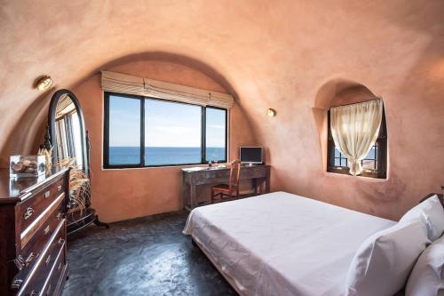 a bedroom with a bed and a desk and a window at Ramni House: Private Villa with pool by the Sea in Oia