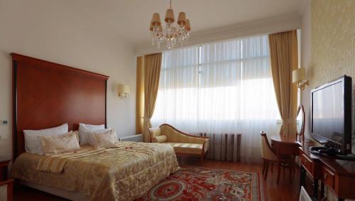 a bedroom with a bed and a television and a chandelier at Apart-hotel Integra in Banja Luka