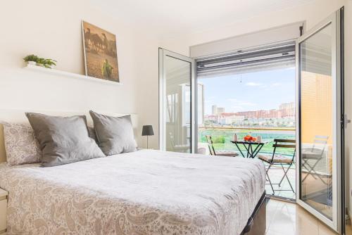een witte slaapkamer met een bed en een balkon bij Home2Book Stylish&Comfy Apartment Rambla, Terrace in Las Palmas de Gran Canaria