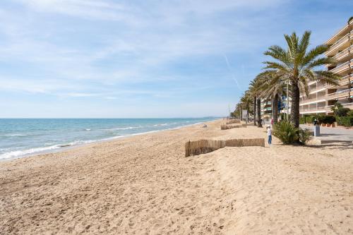 a sandy beach with palm trees and the ocean at The Sunset Calafell in Calafell