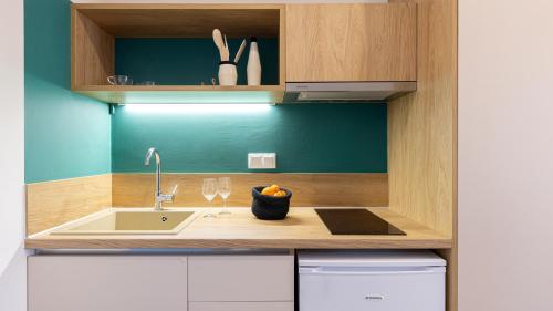 a kitchen counter with a sink and wine glasses at Aether Green Apartments in Nea Roda