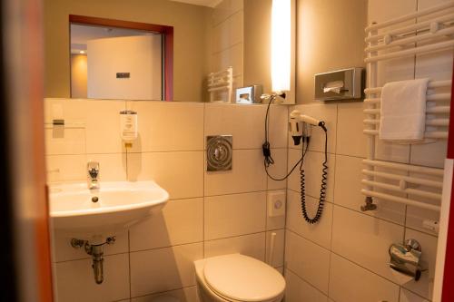 La salle de bains est pourvue d'un lavabo, de toilettes et d'un miroir. dans l'établissement Hotel Sportforum, à Rostock