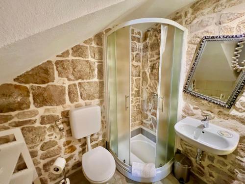 a stone bathroom with a shower and a sink at City Rooms Šibenik in Šibenik