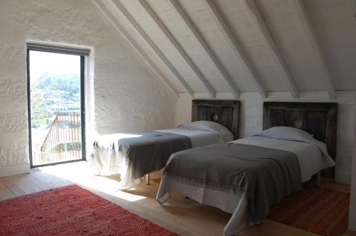 Casa de Cabanelas في Bustelo: سريرين في غرفة مع نافذة كبيرة