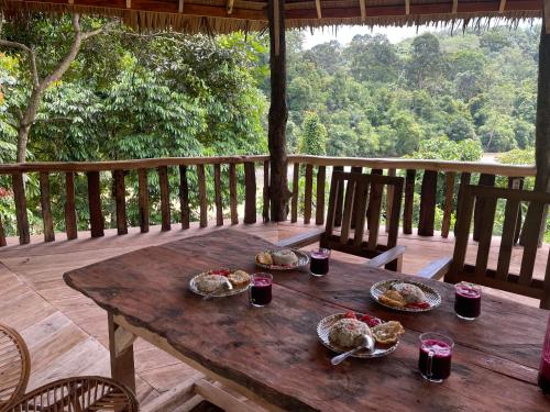 a wooden table with plates of food on a deck at Tangkahan Eco Glamping 