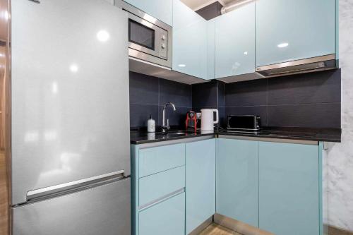 レウスにあるApartments Lilia Reusのキッチン(青いキャビネット、ステンレス製の冷蔵庫付)