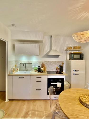 uma cozinha com electrodomésticos brancos e uma mesa de madeira em Le Ludz Blagnac em Blagnac