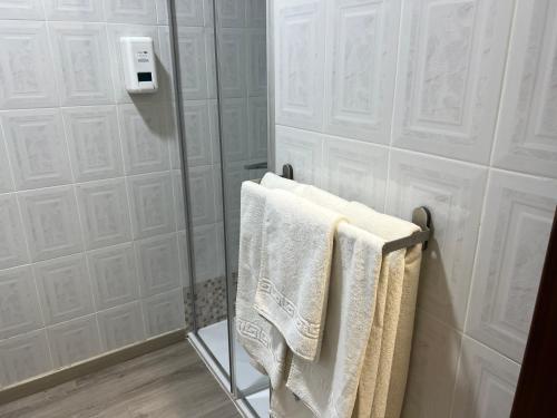 un baño con toallas blancas en un toallero. en Pension Norte en Portugalete