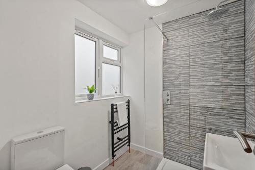 La salle de bains est pourvue d'une porte de douche en verre et d'un lavabo. dans l'établissement 2BR Barnet Gem with Front Garden, à Barnet
