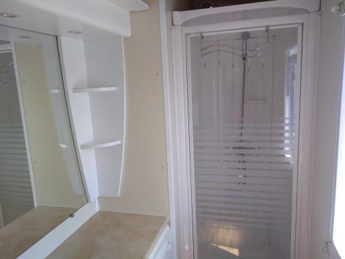 a white closet with a glass door and a mirror at Mobilhome Plouguerneau in Plouguerneau