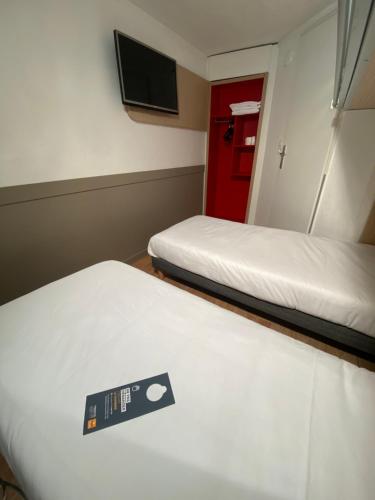 a room with two beds and a tv on the wall at Première Classe Nantes Sud - Rezé Aéroport in Rezé