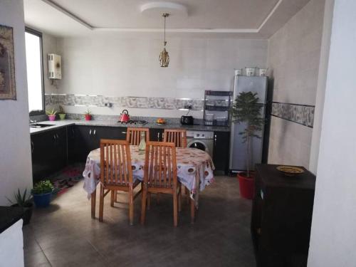 阿加迪尔Chez Maryam , pour les familles à 10 minutes de la plage的配有桌椅和冰箱的厨房