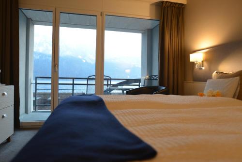 a hotel room with a bed and a large window at Seehotel Riviera at Lake Lucerne in Gersau