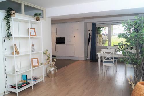 a kitchen and dining room with a table and white shelves at Have a nice stay! - Souterrain The Freesia in Noordwijk