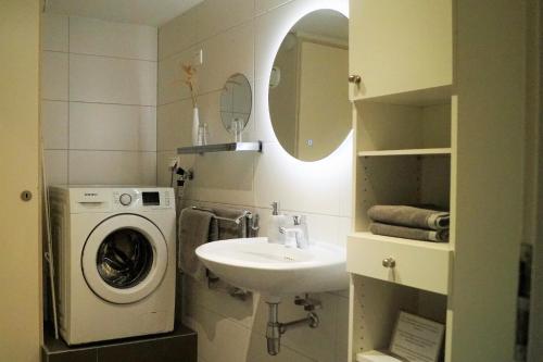 a bathroom with a washing machine and a sink at Have a nice stay! - Souterrain The Freesia in Noordwijk