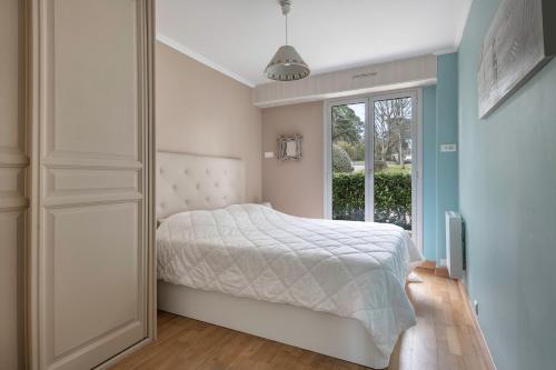 1 dormitorio con cama blanca y ventana en Appartement face mer pour 4 personnes, en Pornic