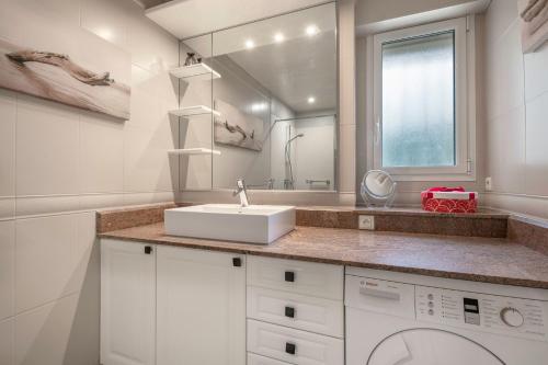 une salle de bain blanche avec un lavabo et un miroir dans l'établissement Appartement face mer pour 4 personnes, à Pornic