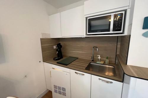 une petite cuisine avec un évier et un micro-ondes dans l'établissement Studio Résidence des Marronniers, à Quiberon