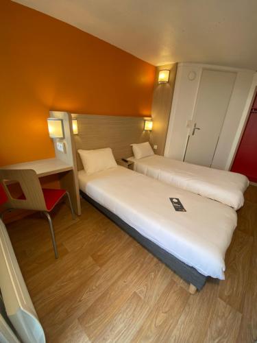 a hotel room with two beds and a desk at Première Classe Nantes Sud - Rezé Aéroport in Rezé