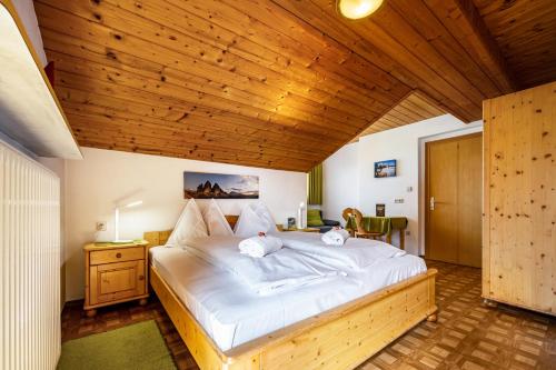 a bedroom with a large white bed with a wooden ceiling at Manuel's Alpenrose in Sesto