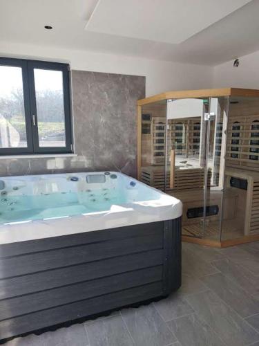 ein großes Bad mit einer großen Badewanne und einem Fenster in der Unterkunft Green Luxury with heated pool, jacuzzi & sauna in Ružići