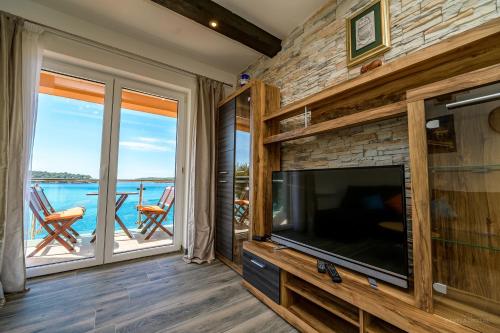 a living room with a large television and a balcony at Villa Magnolia in Mali Lošinj