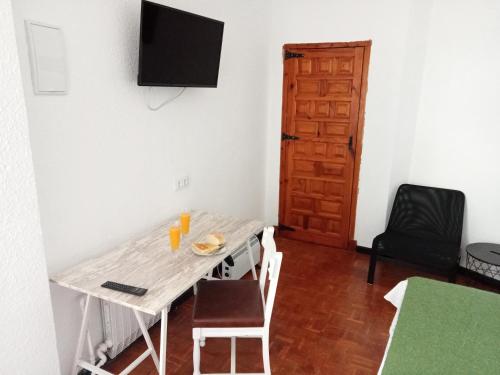 アーロにあるPortal De La Riojaのテーブル、椅子、壁掛けテレビが備わる客室です。