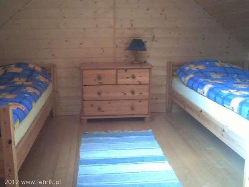 a bedroom with two beds and a dresser and a lamp at Rybacka chata in Rusinowo