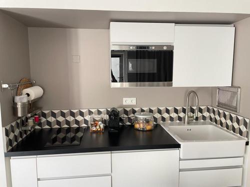 a kitchen with a black counter top and a sink at Le bonheur de la campagne à la ville - Grand studio en plein coeur de la ville in Nîmes