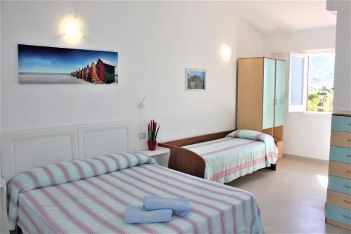 a bedroom with two beds and a tv on the wall at Residence Vardano in Parghelia