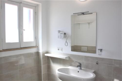 a white bathroom with a sink and a mirror at Residence Vardano in Parghelia