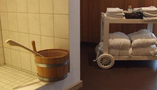 a bathroom with a bucket and a rack of towels at Landgasthof Osterseen in Iffeldorf