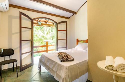 um quarto com uma cama, uma mesa e uma janela em Sítio Borges em Petrópolis