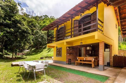 a yellow house with a table and chairs at Sítio Borges in Petrópolis