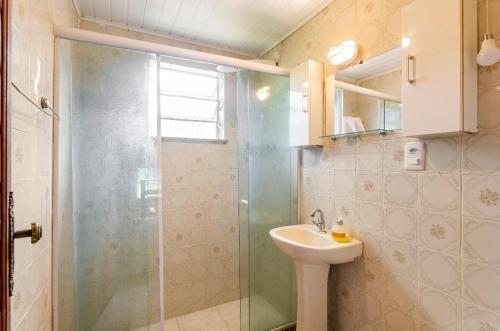 uma casa de banho com uma cabina de duche em vidro e um lavatório. em Sítio Borges em Petrópolis