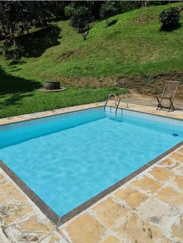 a large blue swimming pool with a bench next to it at Sítio Borges in Petrópolis