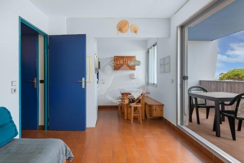 - une chambre avec une porte bleue, une table et des chaises dans l'établissement AS22777- Studio cabine dans une résidence de standing direct sur plage sud, au Grau-du-Roi
