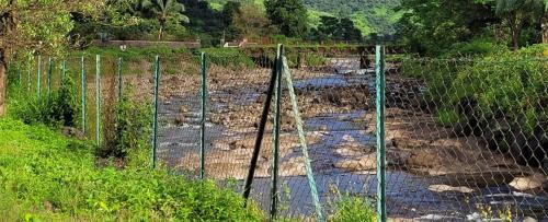 a fence in the middle of a muddy field at The Riverstone Agro Farm in Vajapūr