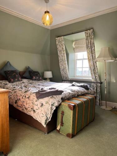 a bedroom with a bed with a mirror and a suitcase at A charming, well appointed Edwardian Gate Lodge in Alyth