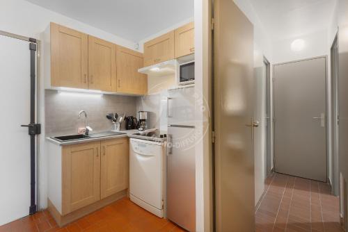 - une petite cuisine avec des appareils blancs et des armoires en bois dans l'établissement AS22429 - P2 Cabine avec terrasse et jardin privatif, au Grau-du-Roi