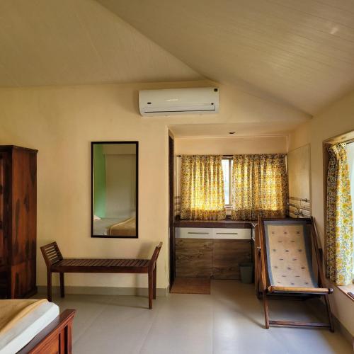 a room with a bed and a bench and a mirror at The Riverstone Agro Farm in Vajapūr