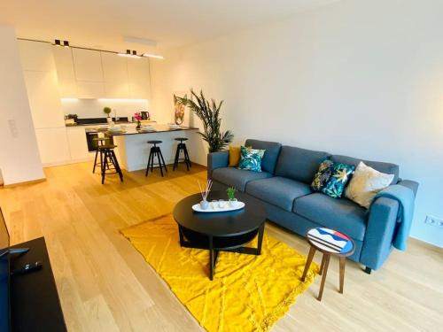 a living room with a blue couch and a table at Luxury Brand New Flat with Terrace & Parking - RTL1 in Luxembourg