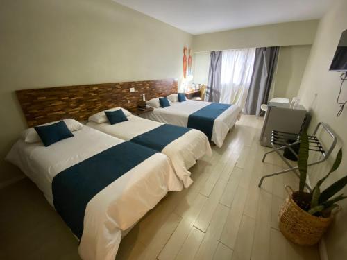 a hotel room with two beds and a large window at La Mision Posadas in Posadas